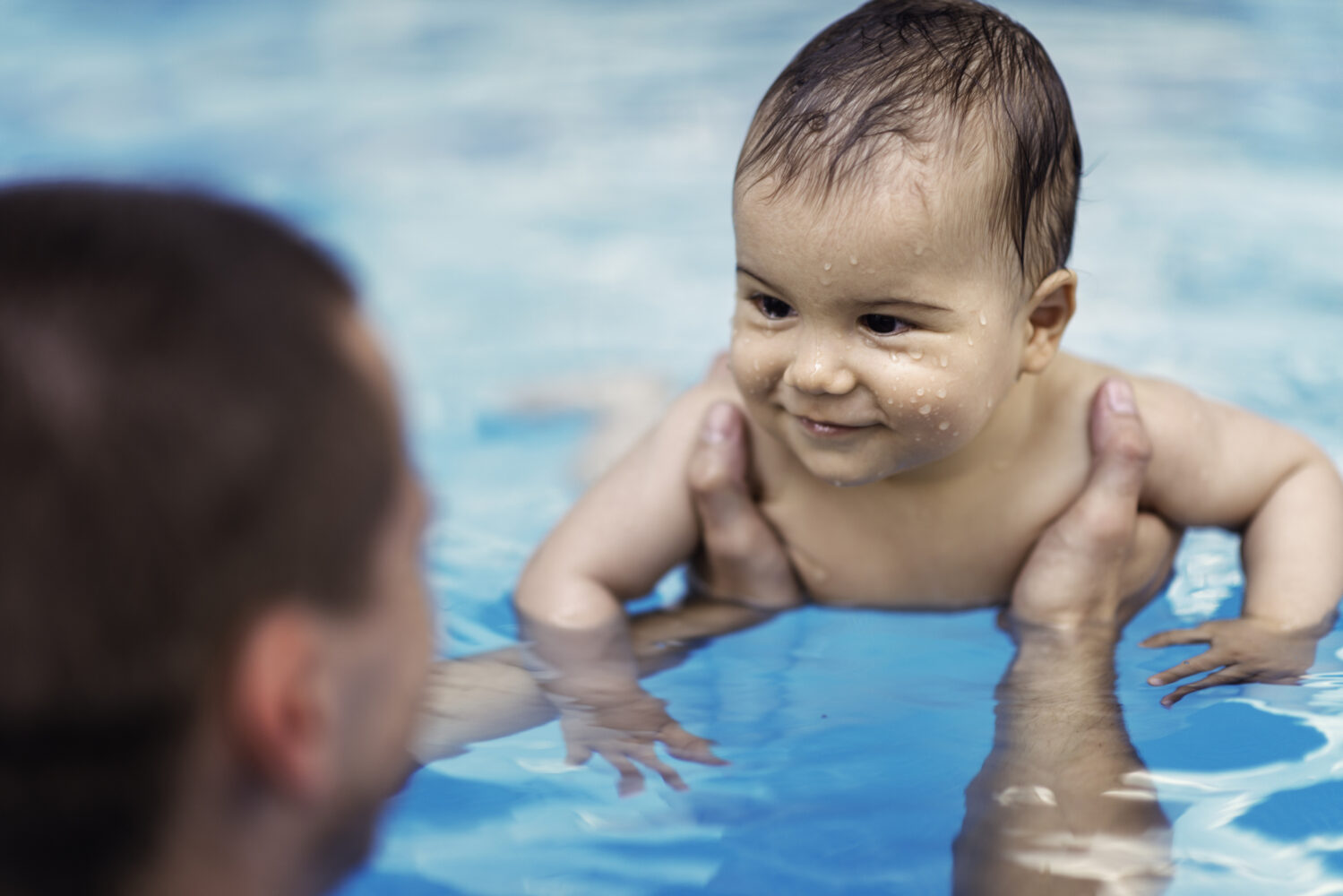 Baby receiving swimming lessons in pool.